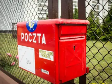 Czerwona skrzynka pocztowa, na której widnieje napis "POCZTA", skrywa tajemnicę korespondencji. Obok znajduje się naklejka "PRZESYŁKI LISTOWE WYJMUJE SIĘ".