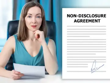 Kobieta w biurze trzyma dokument, obok widoczny formularz umowy NDA.