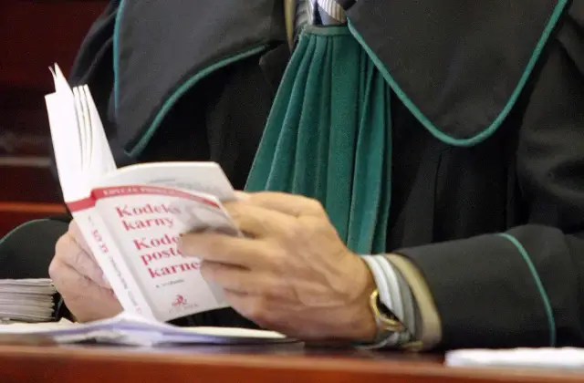 Prawnik w todze czyta Kodeks karny.