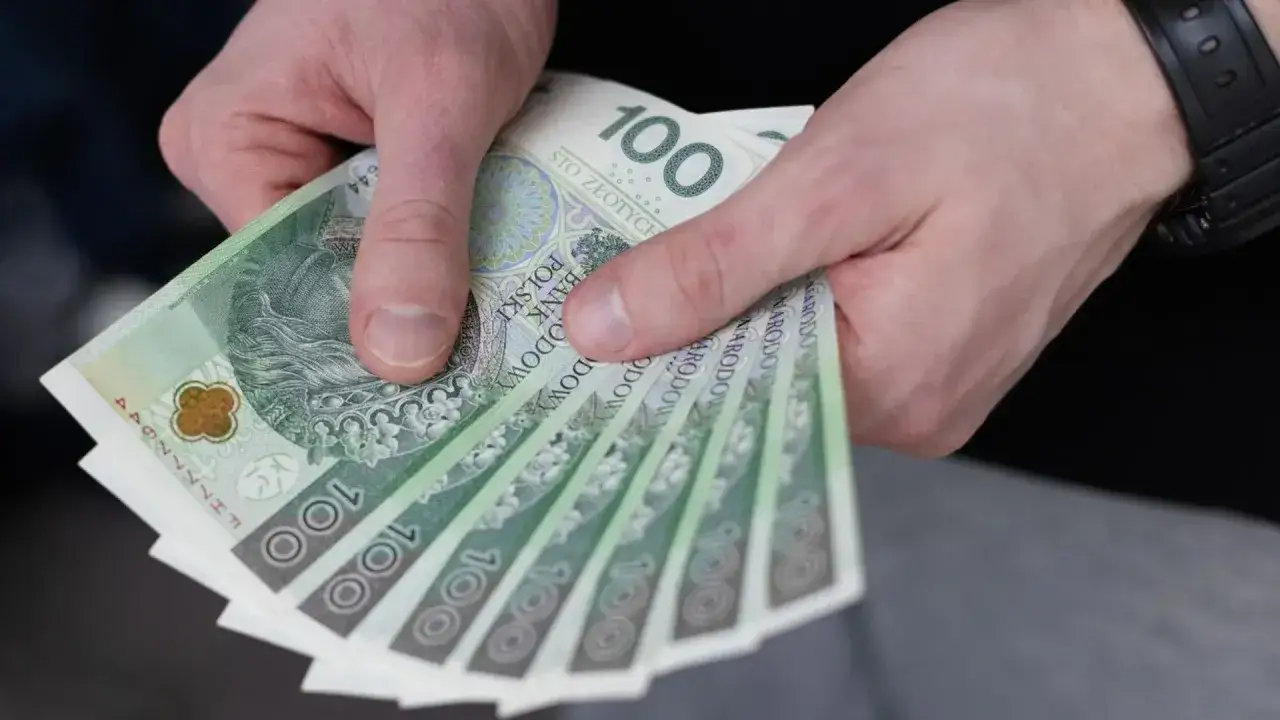 Dłonie trzymające stos banknotów 100 zł. Pieniądze mogą pomóc w pokryciu kosztów leczenia i rehabilitacji, co przysługuje osobie chorej na padaczkę.