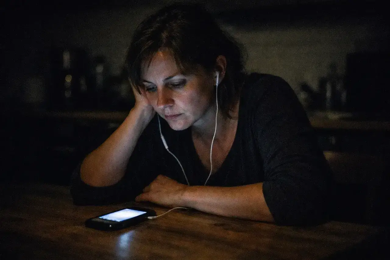 Kobieta w słuchawkach patrzy na telefon. Czy można kogoś nagrywać kamerą bez jego zgody?